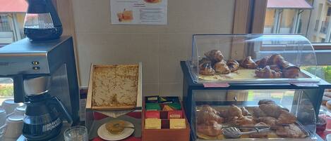 A breakfast buffet with a coffee machine, honeycomb, and various pastries.