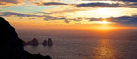 A coastal sunset with rocky cliffs and calm sea.