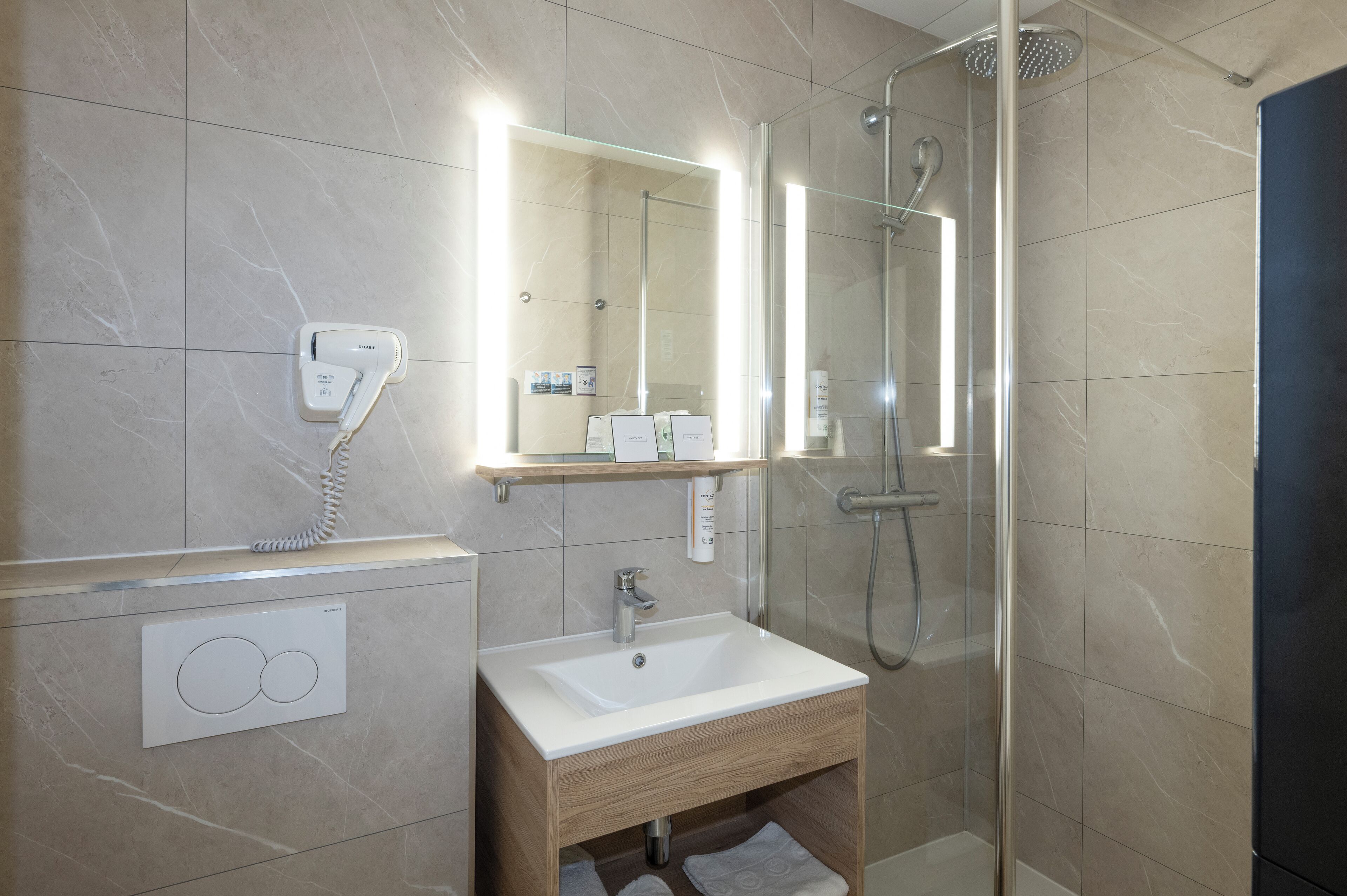 A modern bathroom with a glass-enclosed shower, a white sink, and a mirror above it.