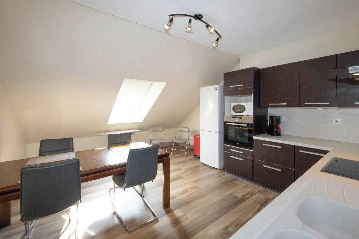 Una cocina compacta con comedor, equipada con refrigerador, horno y cafetera.