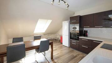 Una cocina compacta con comedor, equipada con refrigerador, horno y cafetera.