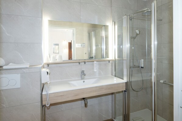 A modern bathroom with a sink, mirror, and glass-enclosed shower.