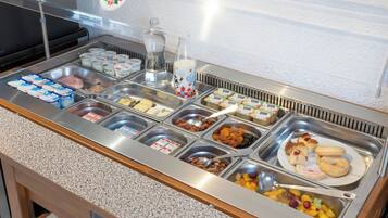 Un bufé con diversas opciones de comida, incluyendo yogur, frutas, frutos secos y pasteles.