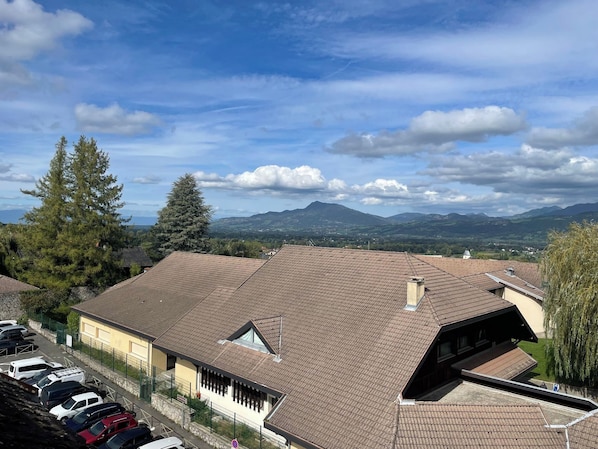 A residential area with a row of houses, a parking lot, and a mountainous landscape in the background. - Hôtel Les Afforêts (La Roche-sur-Foron)