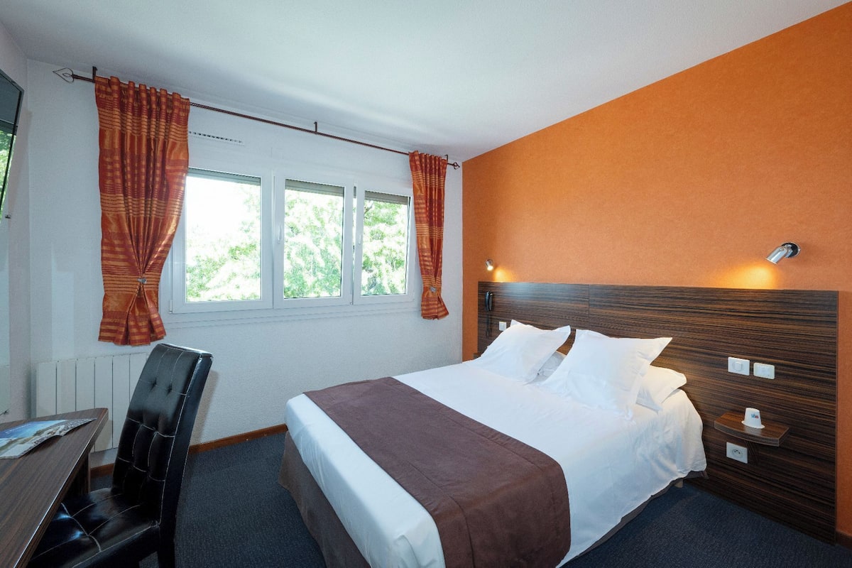 Una habitación de hotel con una cama, un escritorio y una silla.