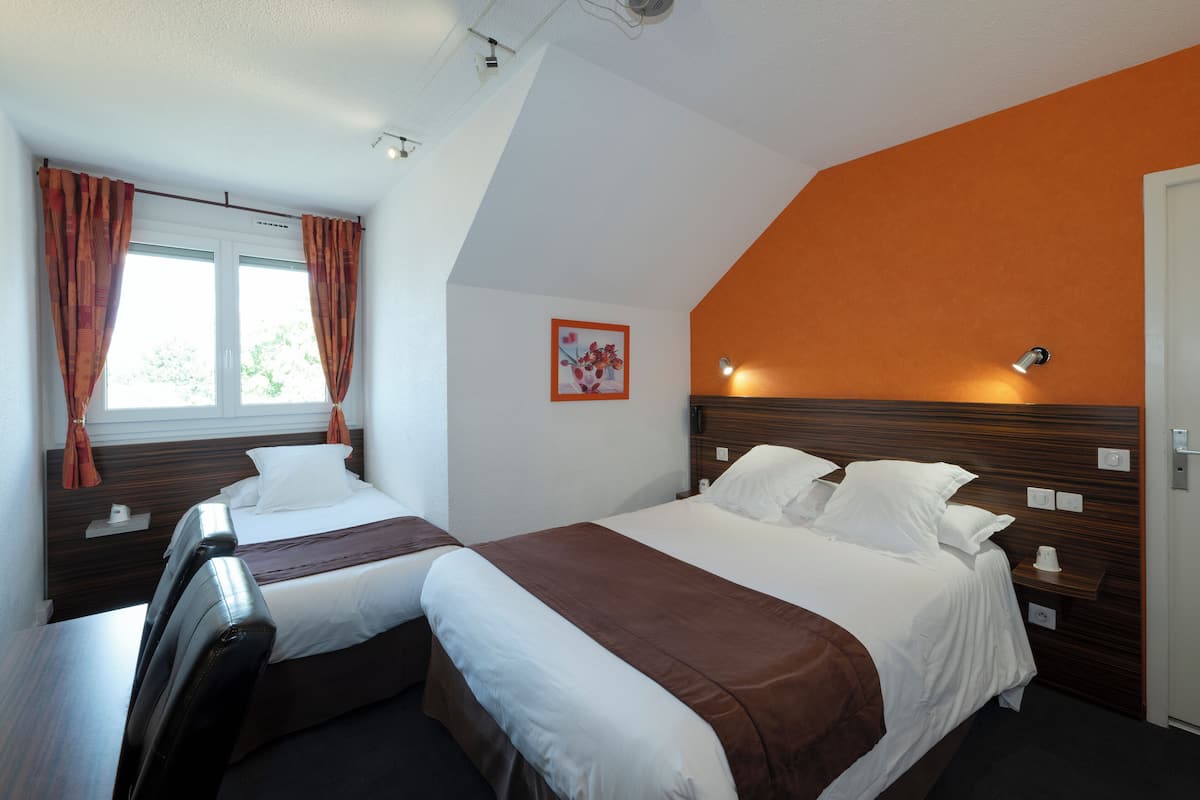 Una habitación de hotel con dos camas, una ventana con cortinas, una lámpara de pared y un cuadro pequeño.