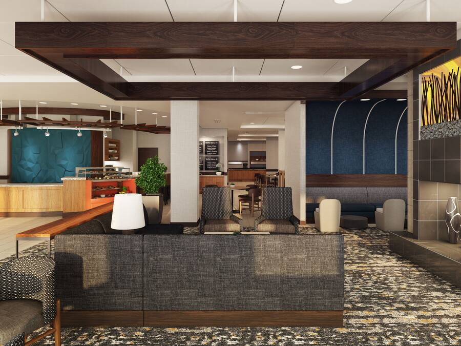 Un moderno vestíbulo de hotel con una recepción, zona de estar y una kitchenette.