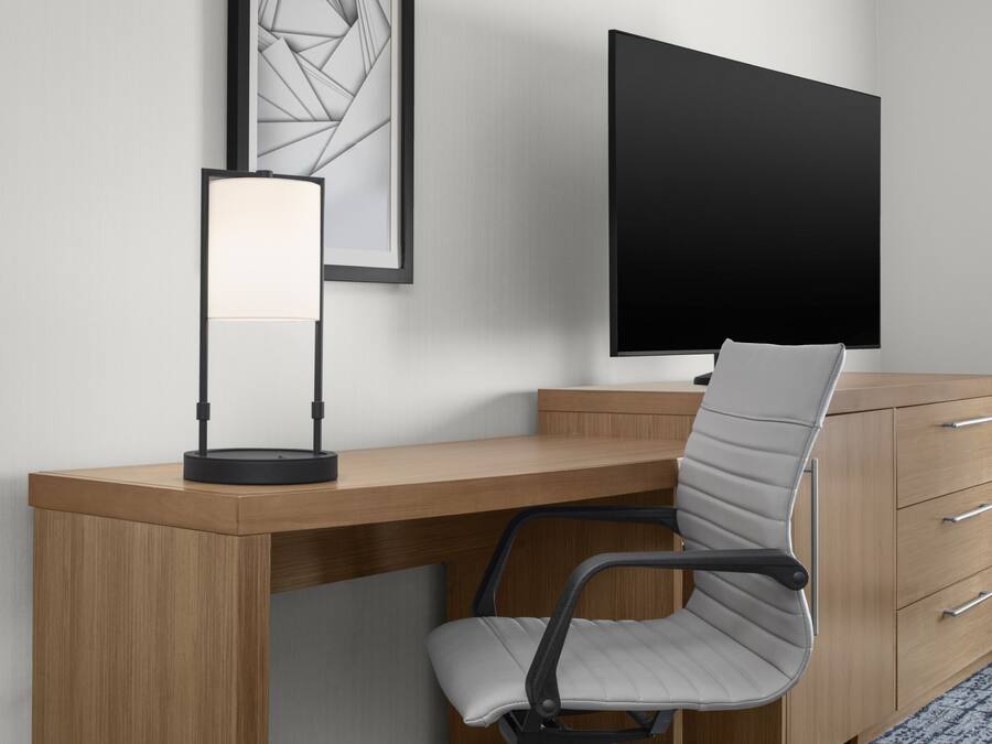A modern office desk with a computer monitor, a lamp, and a chair.
