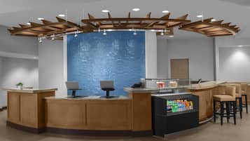 A reception area with a wooden counter, two computer stations, a blue textured wall, and a ceiling with wooden beams and lights.
