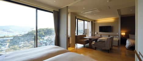 A hotel room with two beds, a desk, a chair, a TV, and a view of a cityscape.