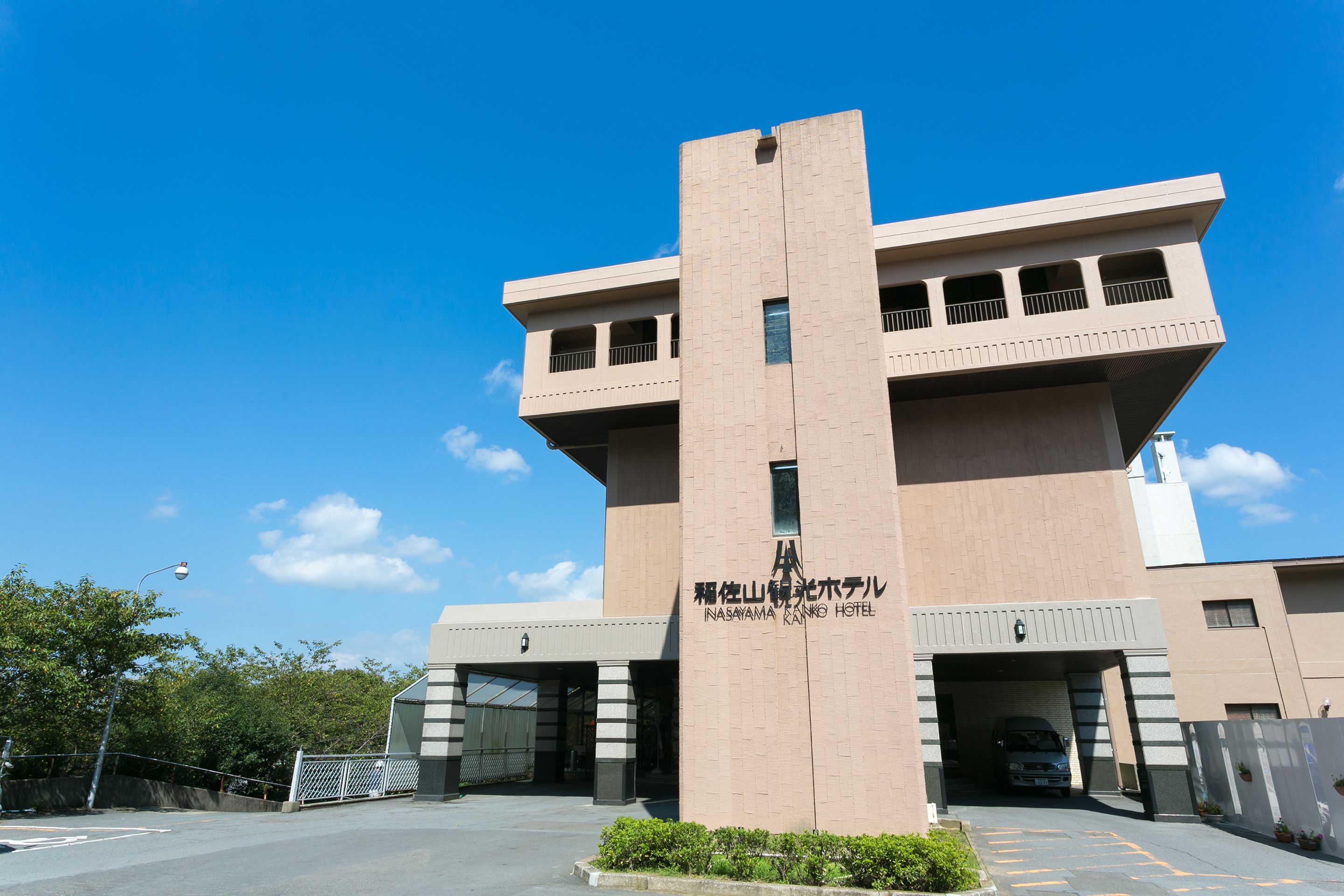 Un bâtiment moderne doté d’une tour centrale et d’une enseigne indiquant « Inasayama Bank Hotel ».
