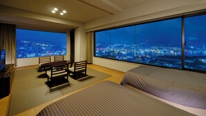 A hotel room with a large window offering a city view at night. - Inasayama Kanko Hotel (Nagasaki)