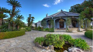 A traditional Japanese-style building with a tiled roof, surrounded by lush greenery and a stone pathway leading to the entrance. - Inasayama Kanko Hotel (Nagasaki)