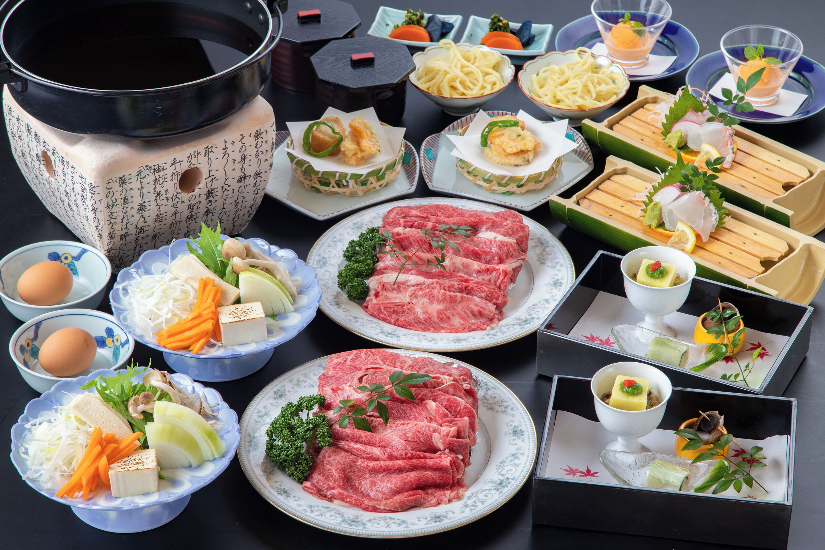 A variety of dishes including raw meat, vegetables, and seafood, arranged on plates and in bowls.