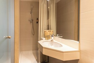 Ein Badezimmer mit Waschbecken, Spiegel, Dusche und einer Tür.