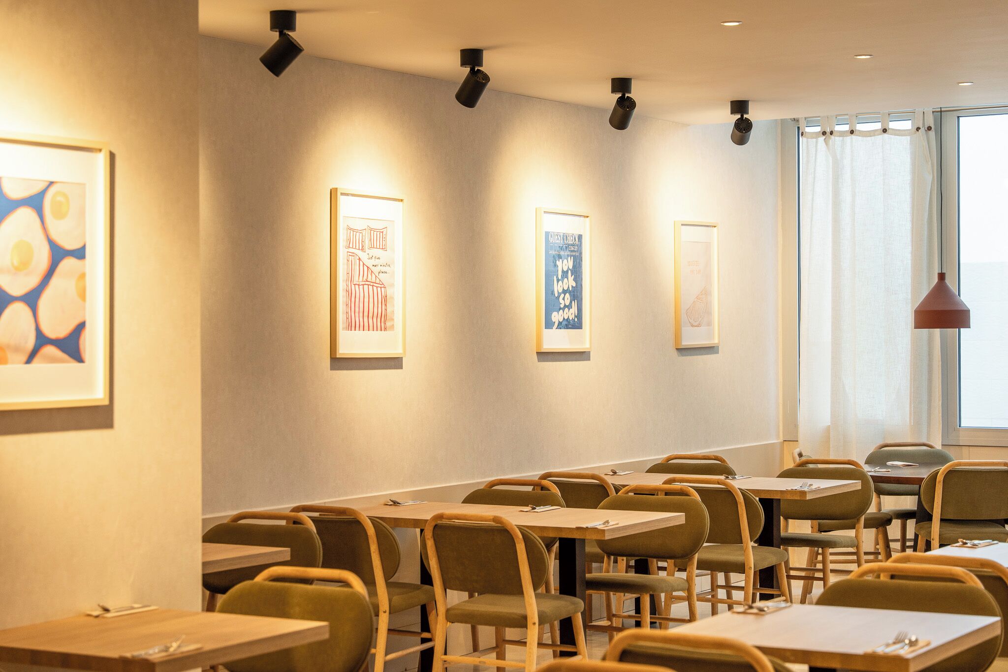 Zona pranzo con tavoli e sedie, opere d'arte appese alle pareti e una finestra con tende.