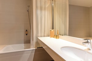 A modern bathroom with a large mirror, a bathtub, and a shower.