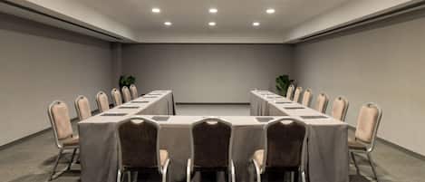 A conference room with a long table, chairs, and ceiling lights.