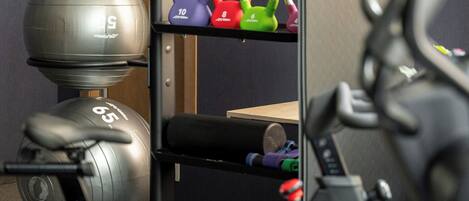A gym with exercise equipment, including kettlebells, a weight bench, and a stationary bike.