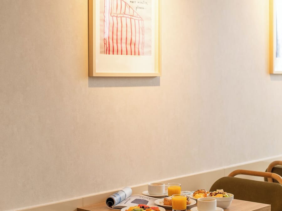 Un comedor con una mesa lista para el desayuno, que incluye platos de comida, tazas y un menú enrollado.