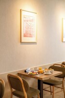 A dining area with a table set for breakfast, including plates of food, cups, and a rolled-up menu.