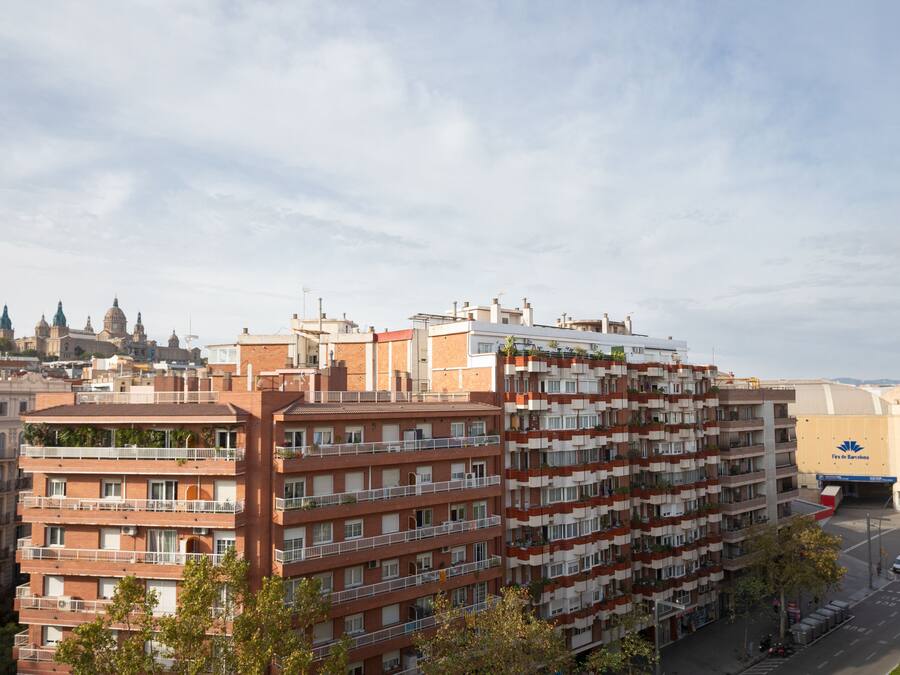 Een meerlaags woongebouw met balkons en een stadsgezicht op de achtergrond.