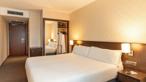 A hotel room with a large bed, bedside lamps, a wooden headboard, a nightstand, a wardrobe, and a mirror. - Arco Barcelona Hotel (Barcelona)