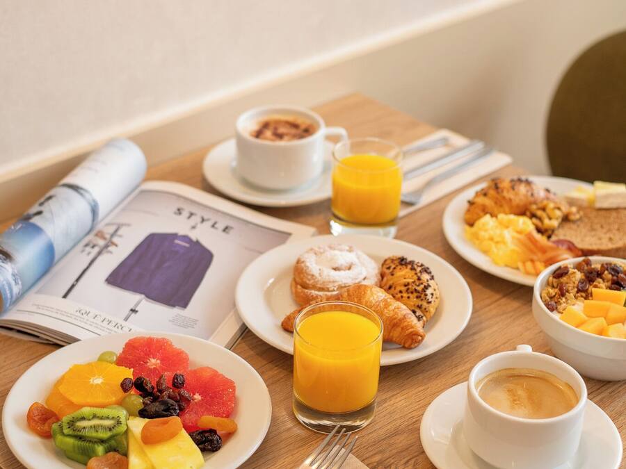 Et morgenbord med forskellige retter, et magasin og en kop kaffe.