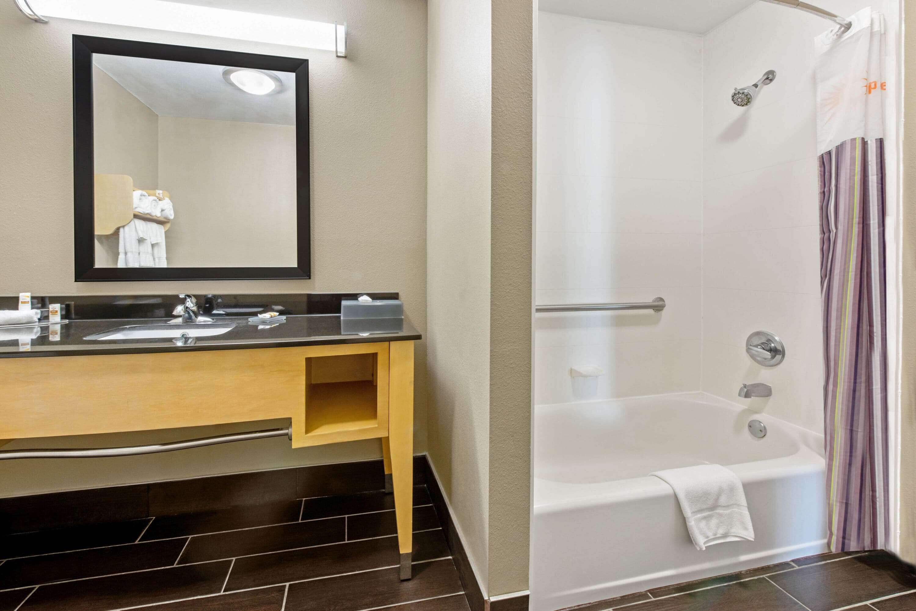 Een badkamer met een wastafel, spiegel en douche.