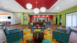 A lobby with a red ceiling, green walls, and a colorful carpet. There are two sofas and a coffee table with a bowl on it. - La Quinta Inn & Suites by Wyndham Leesville Ft. Polk (Leesville)