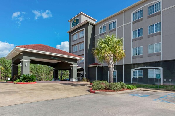 A hotel with a covered entrance, a palm tree, and a parking lot with handicapped parking.