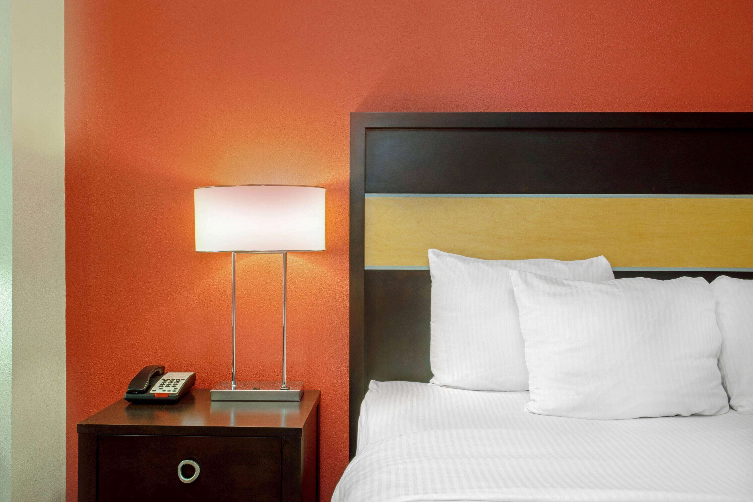 A hotel room with a bed, a nightstand with a lamp, and a telephone.