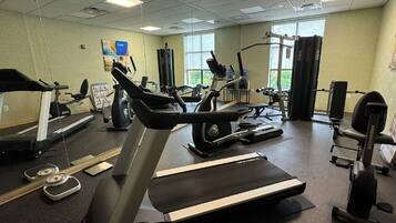 Une salle de sport équipée de tapis de course, de vélos elliptiques et de matériel de musculation.