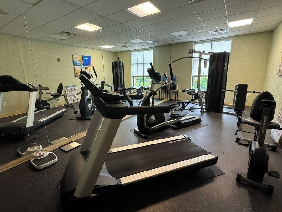 Une salle de sport équipée de tapis de course, de vélos elliptiques et de matériel de musculation.