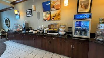 Un comptoir de petit-déjeuner proposant divers aliments, une machine à café et un réfrigérateur où est affiché un menu.