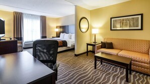 A hotel room with a bed, a sofa, a desk, and a TV.