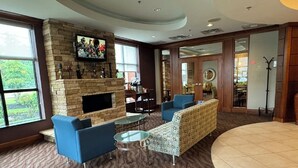 A spacious lobby with a stone fireplace, blue seating, and a television mounted on the wall.