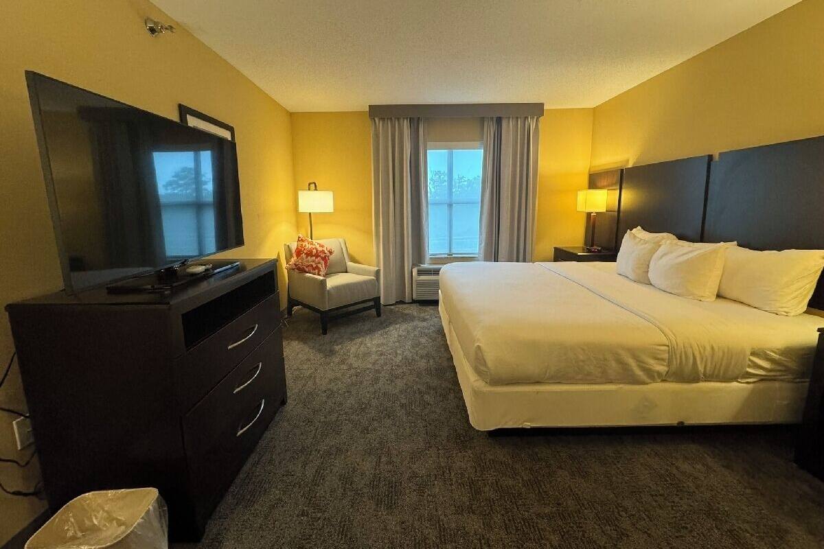 A hotel room with a bed, a TV, a desk, and a chair.