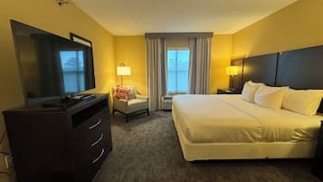 A hotel room with a bed, a TV, a desk, and a chair.