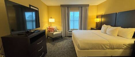 A hotel room with a bed, a TV, a desk, and a chair.