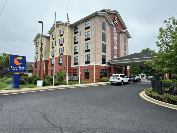 A Comfort Inn & Suites hotel with a brick facade, multiple floors, and a covered parking area. - Comfort Inn & Suites Lexington Park near Pax River (Lexington Park)