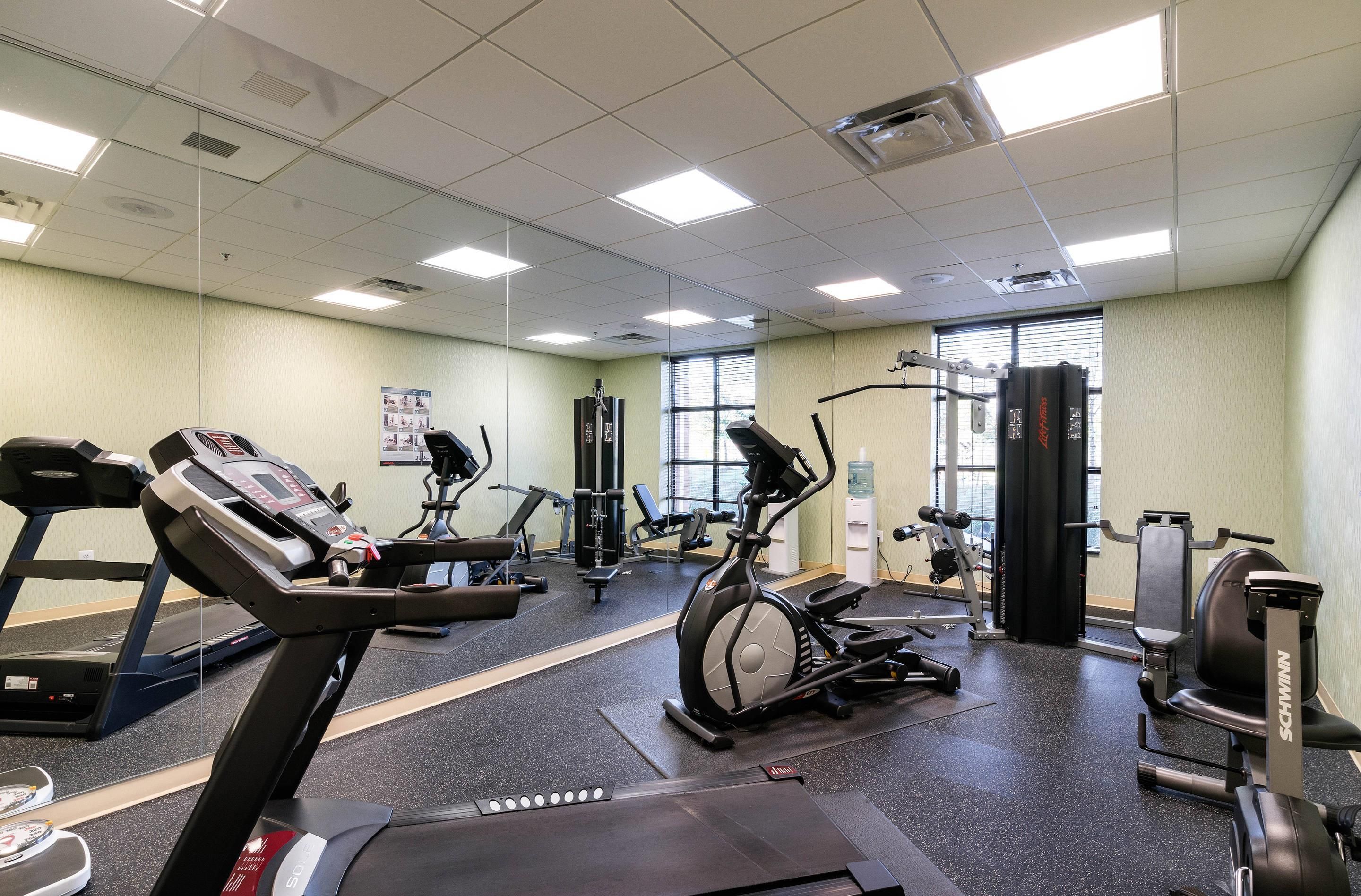 Un gimnasio con cintas de correr, bicicletas estáticas y máquinas de pesas.