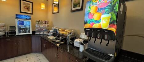 Una estación de autoservicio para bebidas con múltiples dispensadores, una cafetera y un panel de menú digital.