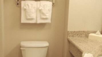 Une salle de bain équipée de toilettes, d’un porte-serviettes avec des serviettes et d’un comptoir en granit.