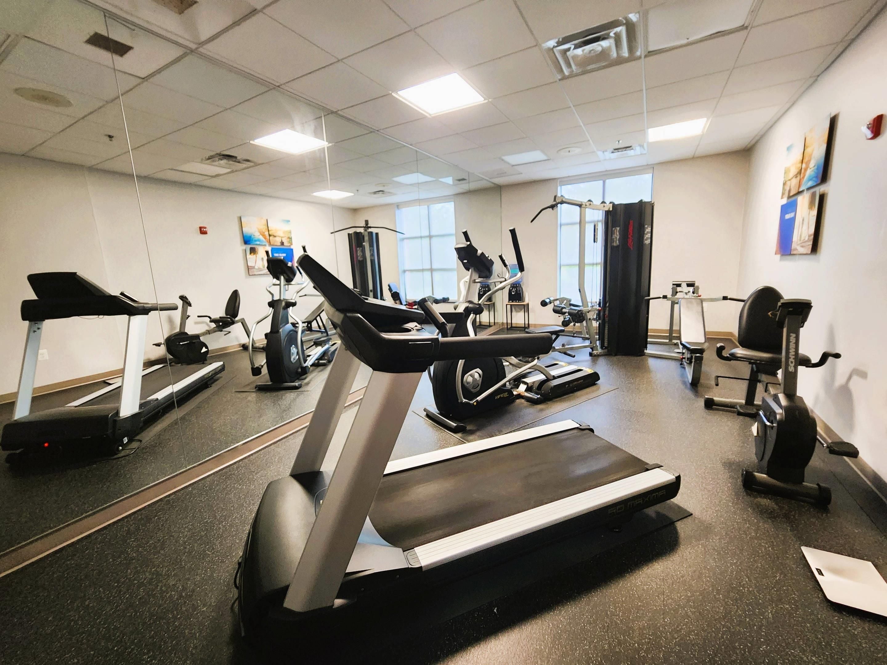 Un gimnasio con cintas de correr, elípticas y equipo de pesas.