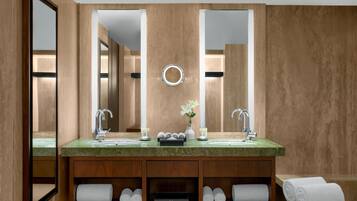 A modern bathroom with a large mirror, two sinks, and a vanity with shelves for towels.