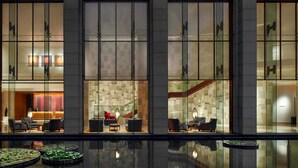Un moderno vestíbulo de hotel con mostrador de recepción, zona de estar y una escalera.