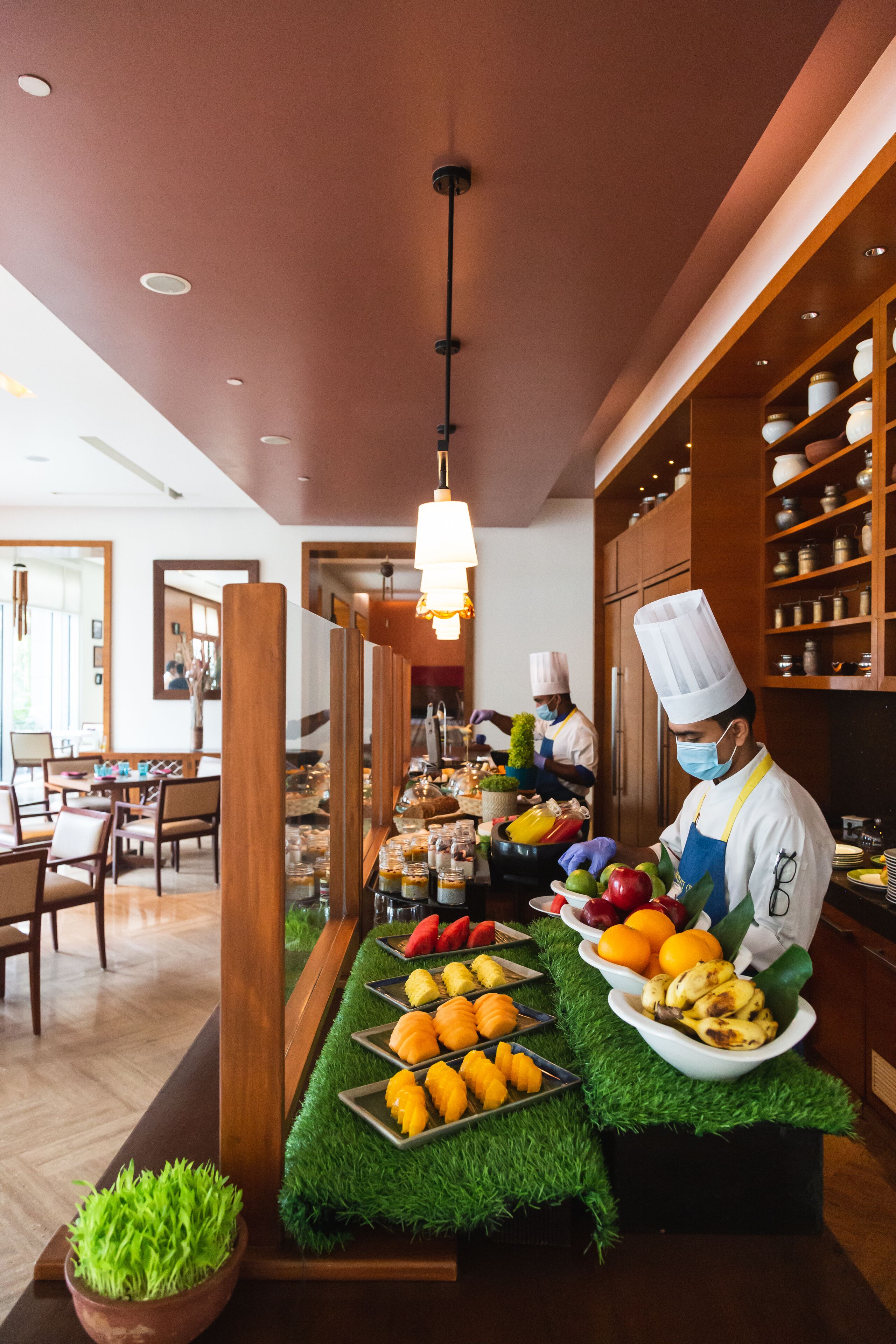 A chef preparing food in a kitchen with a buffet setup.