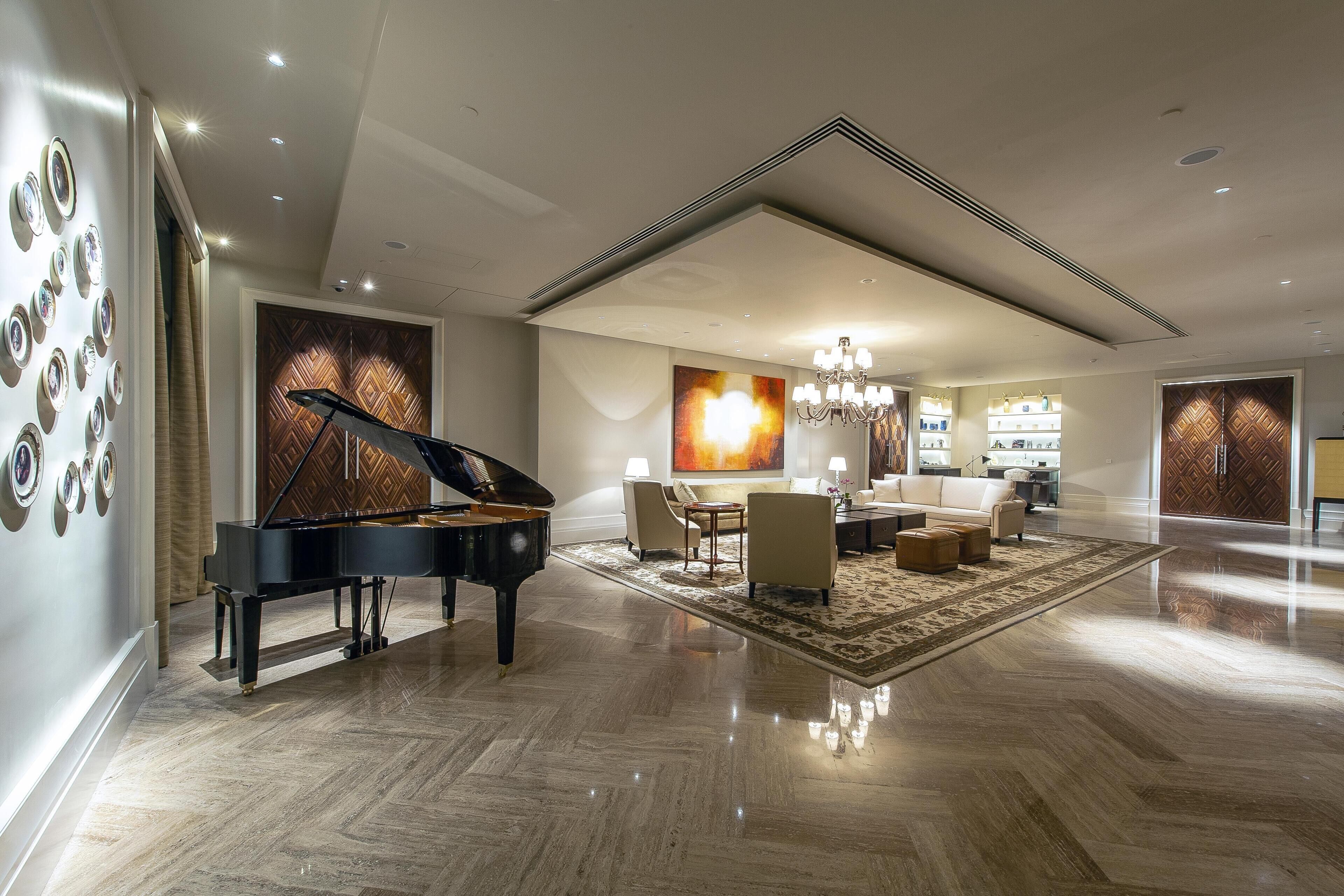 A spacious living room with a grand piano, a chandelier, and a large painting.