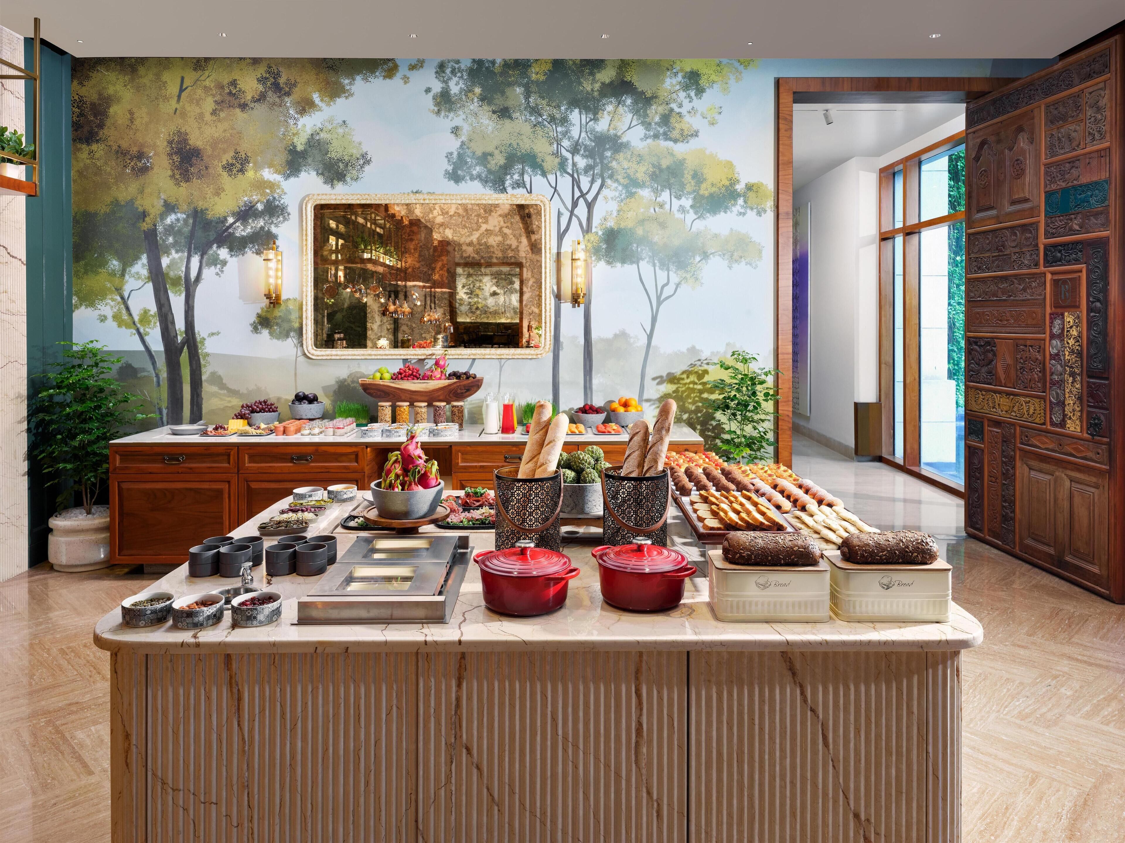 A spacious kitchen with a large island, wooden cabinets, and a mural of a forest scene.